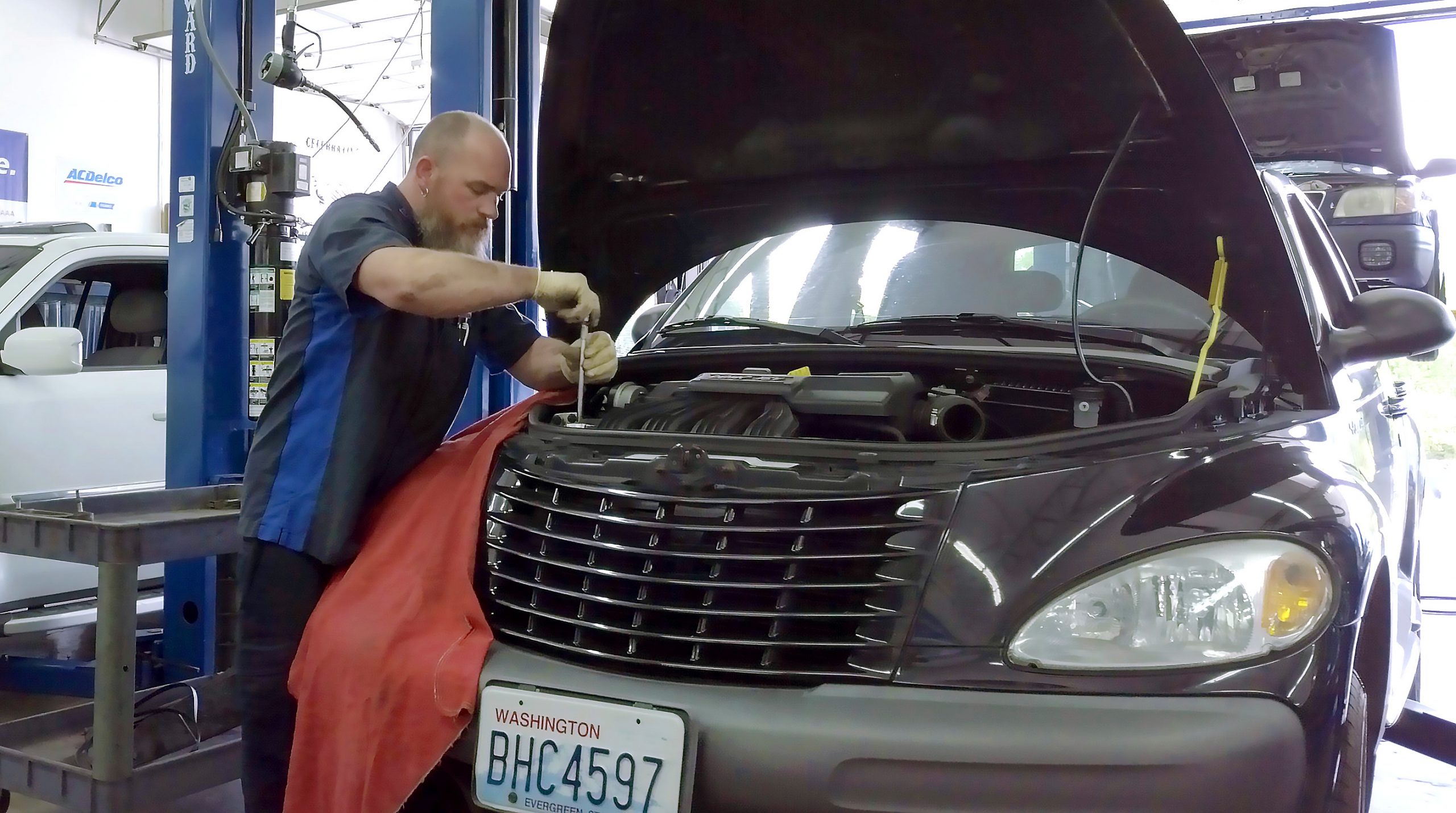 Auto repair technician using a tool to perform vehicle maintenance at Local Wrench Auto Repair in Belfair, WA