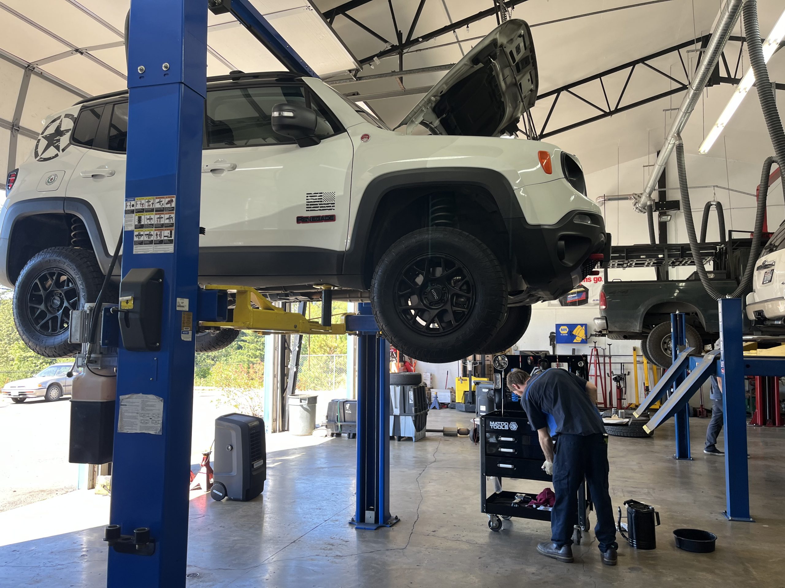Automotive technician servicing a vehicle on a lift at Local Wrench Auto Repair in Belfair