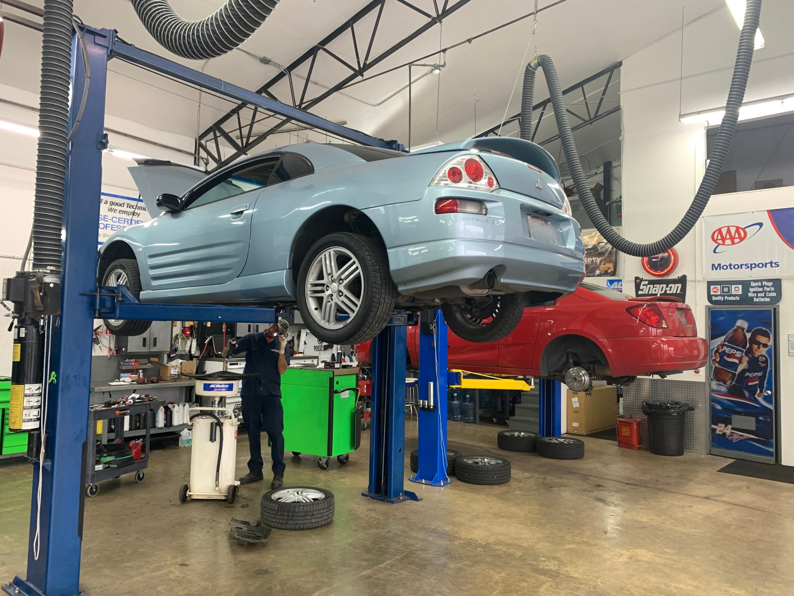 ASE-certified technician draining transmission fluid while performing transmission service under a vehicle on a lift at Local Wrench Auto Repair in Belfair, Washington